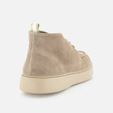 The OFFICINE CREATIVE Frame Suede Lace Chukka Boot, crafted in beige suede, showcases a refined chukka-inspired silhouette with a chunky, light-toned sole and is presented from a rear side angle against a plain white background.