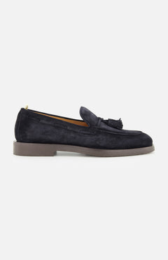 The OFFICINE CREATIVE Opera Flexi Tassel Loafer is crafted in dark blue suede with a tassel detail on top, featuring a round toe and a low heel, and is shown from the side against a plain white background.