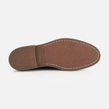 The image shows the bottom view of the Opera Flexi Tassel Loafer by OFFICINE CREATIVE, featuring a brown leather sole with visible stitching around the edge and a textured heel, characteristic of a classic Italian loafer.