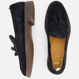 A pair of Opera Flexi Tassel Loafers by OFFICINE CREATIVE, crafted in classic Italian style with black suede uppers—one shown from the side and one from above—featuring brown soles, tan leather insoles adorned with gold brand lettering, and elegant tassel details.