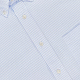 Close-up of the Candy Stripe Oxford Shirt by OFFICINE GÉNÉRALE, crafted in Italian cotton with light blue and white stripes, white buttons, a left chest pocket, and a collar tag—showcasing Parisian sophistication.