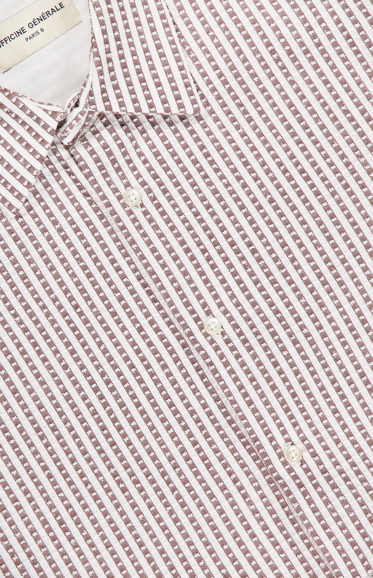 Close-up of the Gad Striped Shirt by OFFICINE GÉNÉRALE, featuring brown and white stripes, a small collar, and three white buttons. The OFFICINE GÉNÉRALE label appears at the neck for a refined casual style.