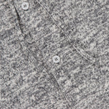 Close-up of the Melange Basile Drawstring Hoodie by OFFICINE GÉNÉRALE, featuring marled grey fabric, a chest patch pocket, white buttons, and a partially visible label at the collar.