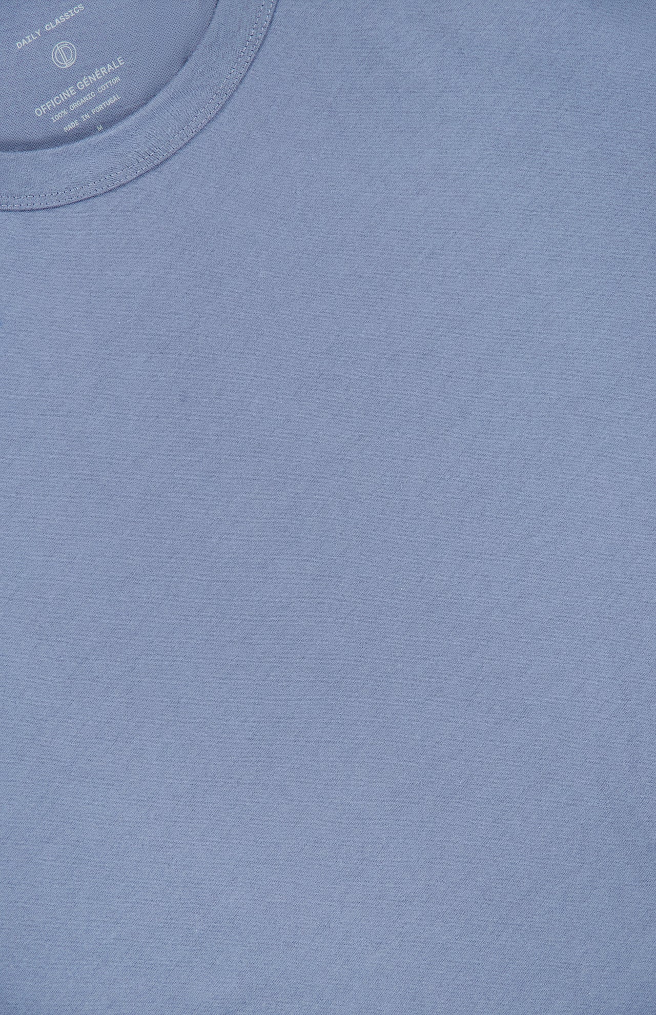 A close-up view of the OFFICINE GÉNÉRALE Cotton Crewneck T-Shirt in light blue, crafted from soft organic cotton, highlighting the classic crew neckline and a small section of the label inside the collar.