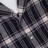 Close-up of the Eren Long Sleeve Gaze Checkered Shirt by OFFICINE GÉNÉRALE, featuring a navy blue, gray, and white plaid pattern with white buttons and a visible OFFICINE GÉNÉRALE PARIS label. Expertly crafted in Portugal, this classic long-sleeved shirt highlights exceptional attention to detail and timeless style.
