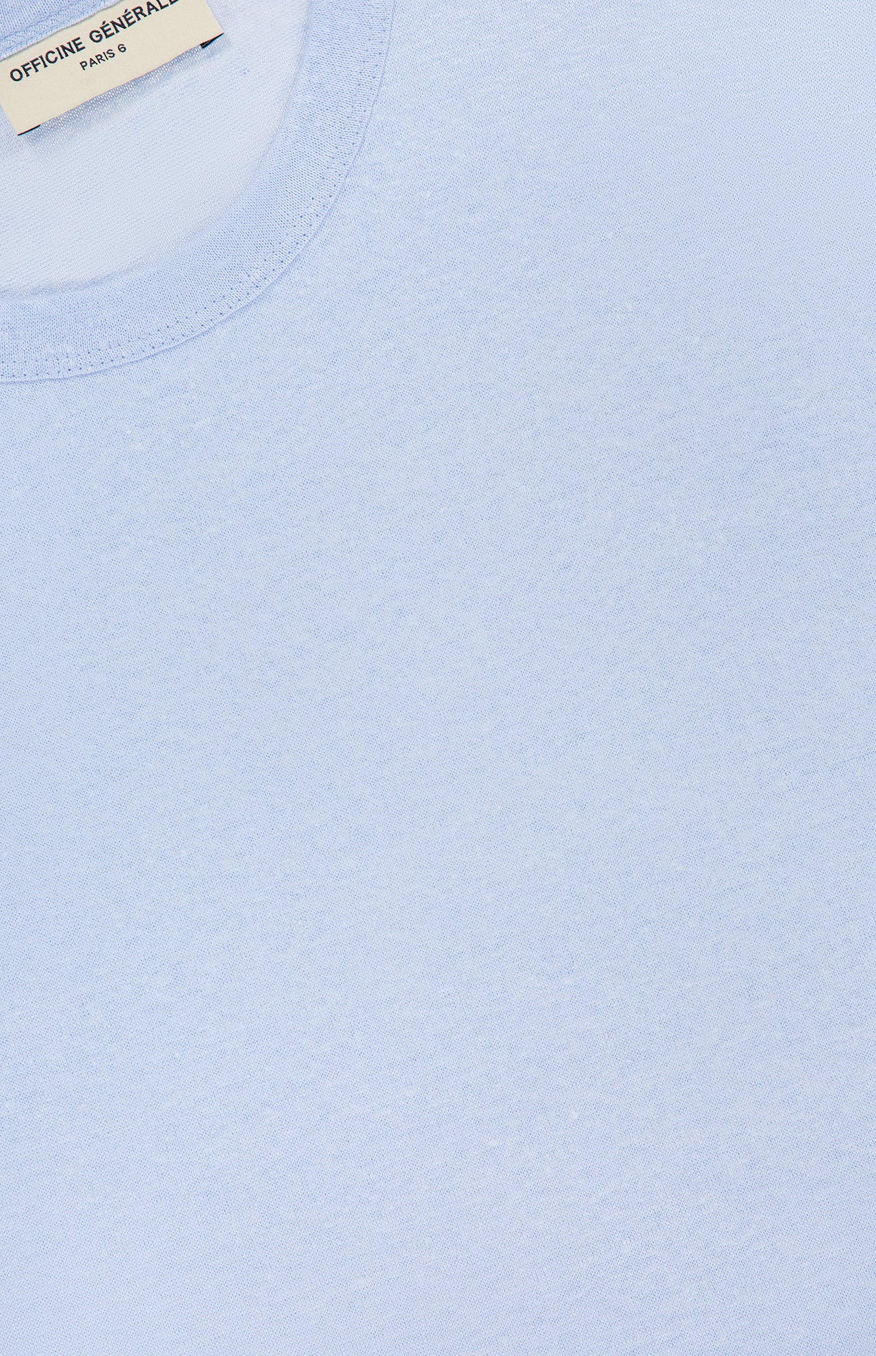 Close-up of the Garment Dyed Linen Short Sleeve T-shirt by OFFICINE GÉNÉRALE in light blue, featuring a visible neck label, soft textured linen fabric, clean stitching, and breathable comfort for summer.