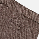 Close-up of the Hoche Wool Trouser Pants by OFFICINE GÉNÉRALE, showcasing a textured light brown finish, detailed stitching, belt loops, and a back pocket with button closure—all set against a white background.