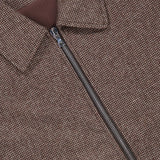 Close-up of the Marlino 2-way Zip Wool Jacket by OFFICINE GÉNÉRALE, featuring a brown textured wool exterior with a zip-up design and a collar. A white label inside the collar displays “OFFICINE GÉNÉRALE PARIS.” The zipper is partially open, revealing the brown inner lining.