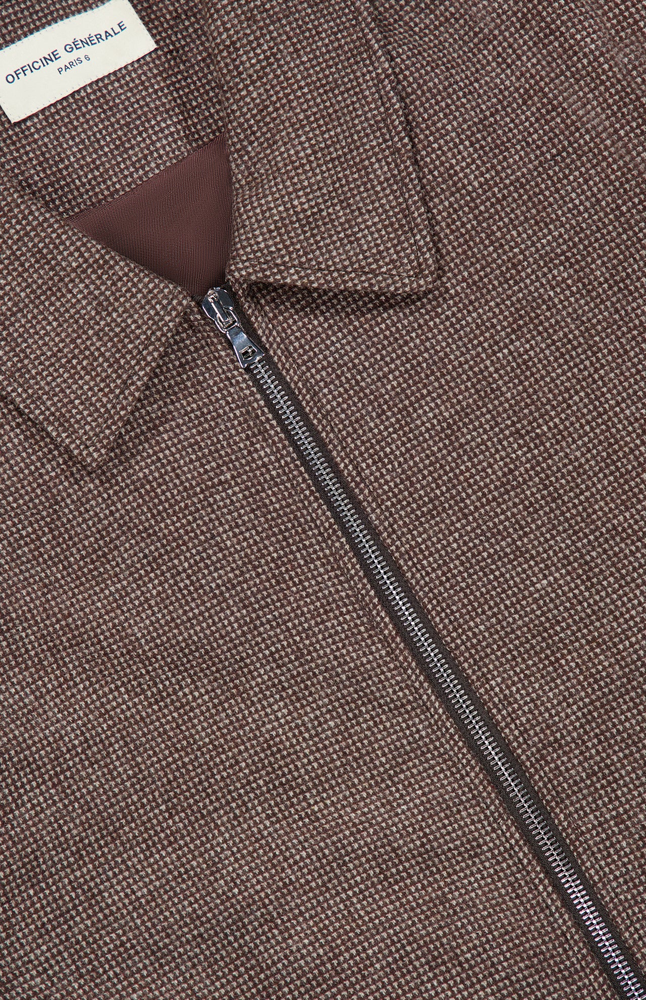 Close-up of the Marlino 2-way Zip Wool Jacket by OFFICINE GÉNÉRALE, featuring a brown textured wool exterior with a zip-up design and a collar. A white label inside the collar displays “OFFICINE GÉNÉRALE PARIS.” The zipper is partially open, revealing the brown inner lining.