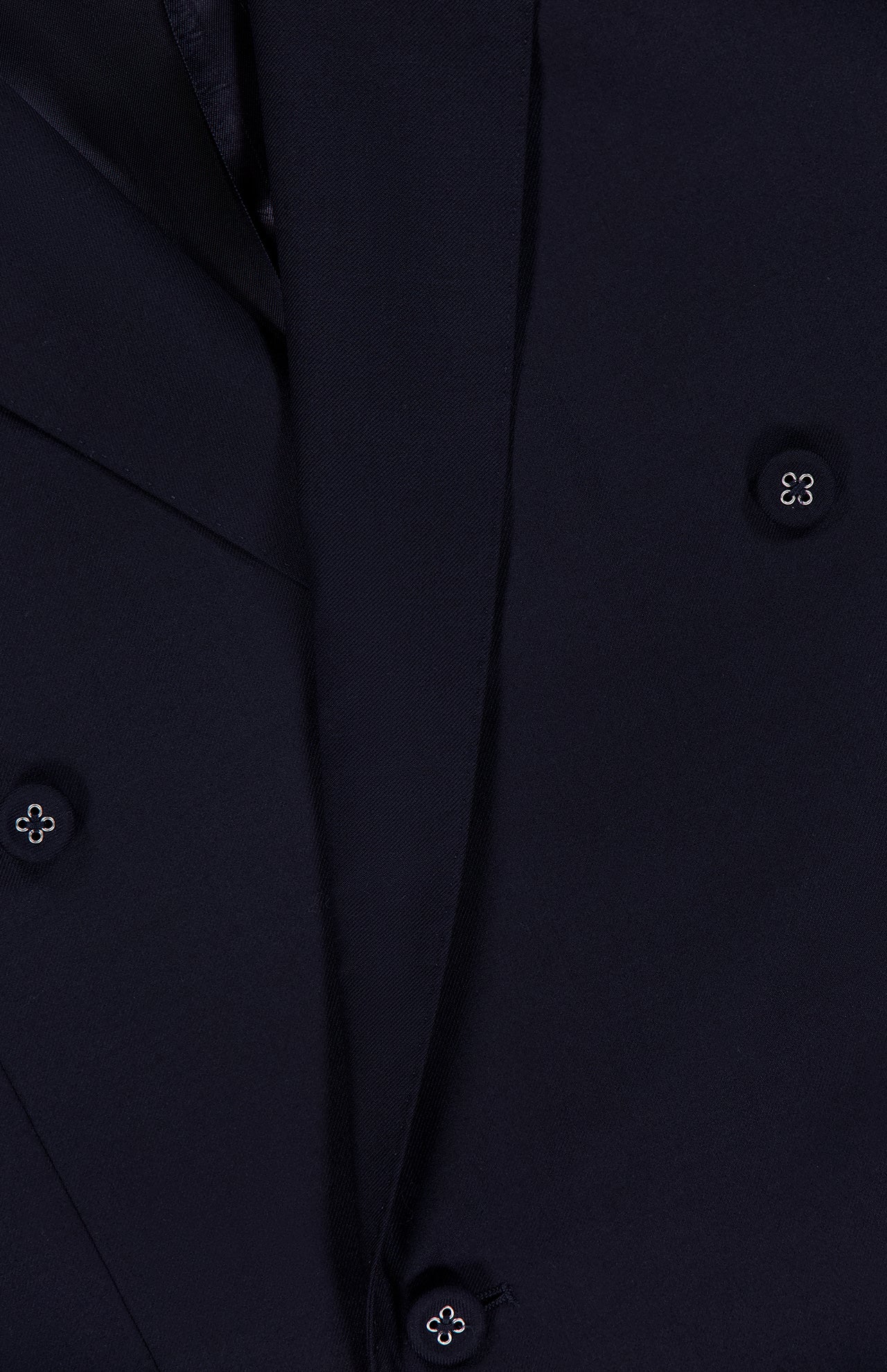 Close-up of the OFFICINE GÉNÉRALE Merrick Twill Double Breasted Jacket in dark navy, highlighting its double-breasted design with four round buttons featuring a small white center detail. The smooth twill fabric showcases the refined texture characteristic of a virgin wool blazer, while partially visible lapels complete the sophisticated look.