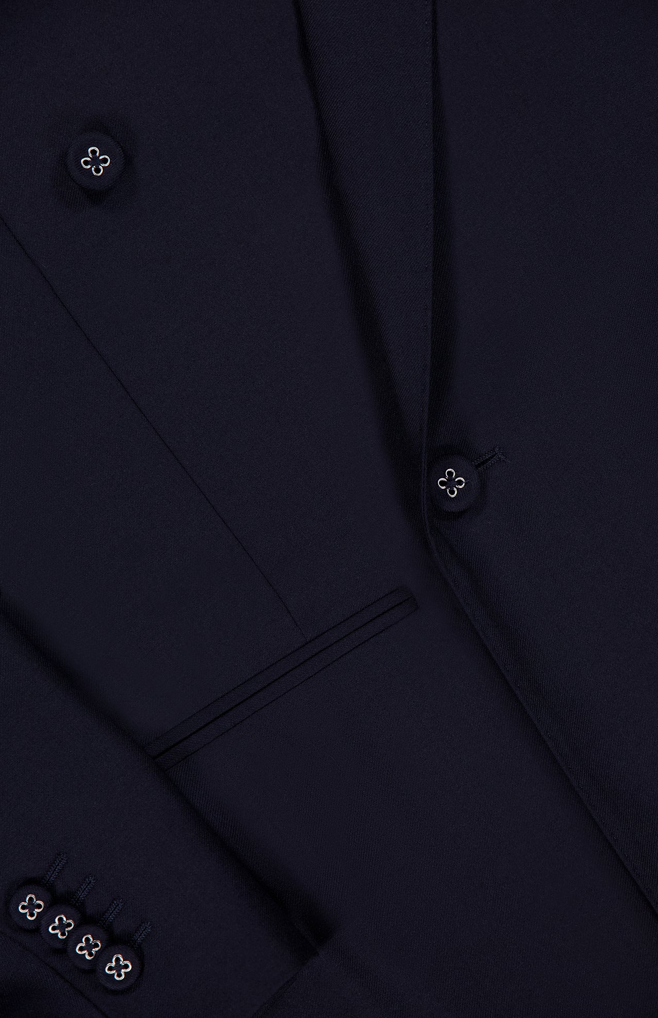 Close-up of the OFFICINE GÉNÉRALE Merrick Twill Double Breasted Jacket in dark navy, highlighting part of the lapel, a pocket, and several buttons on the sleeve and front. This tailored jacket is crafted from premium virgin wool for an elegant finish.