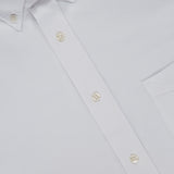 Close-up of a white oxford button-down shirt called the New Oxford Button Down Shirt by OFFICINE CREATIVE, crafted from 100% cotton, featuring a visible chest pocket and pearl-like buttons. The shirt label reads OFFICINE CREATIVE.