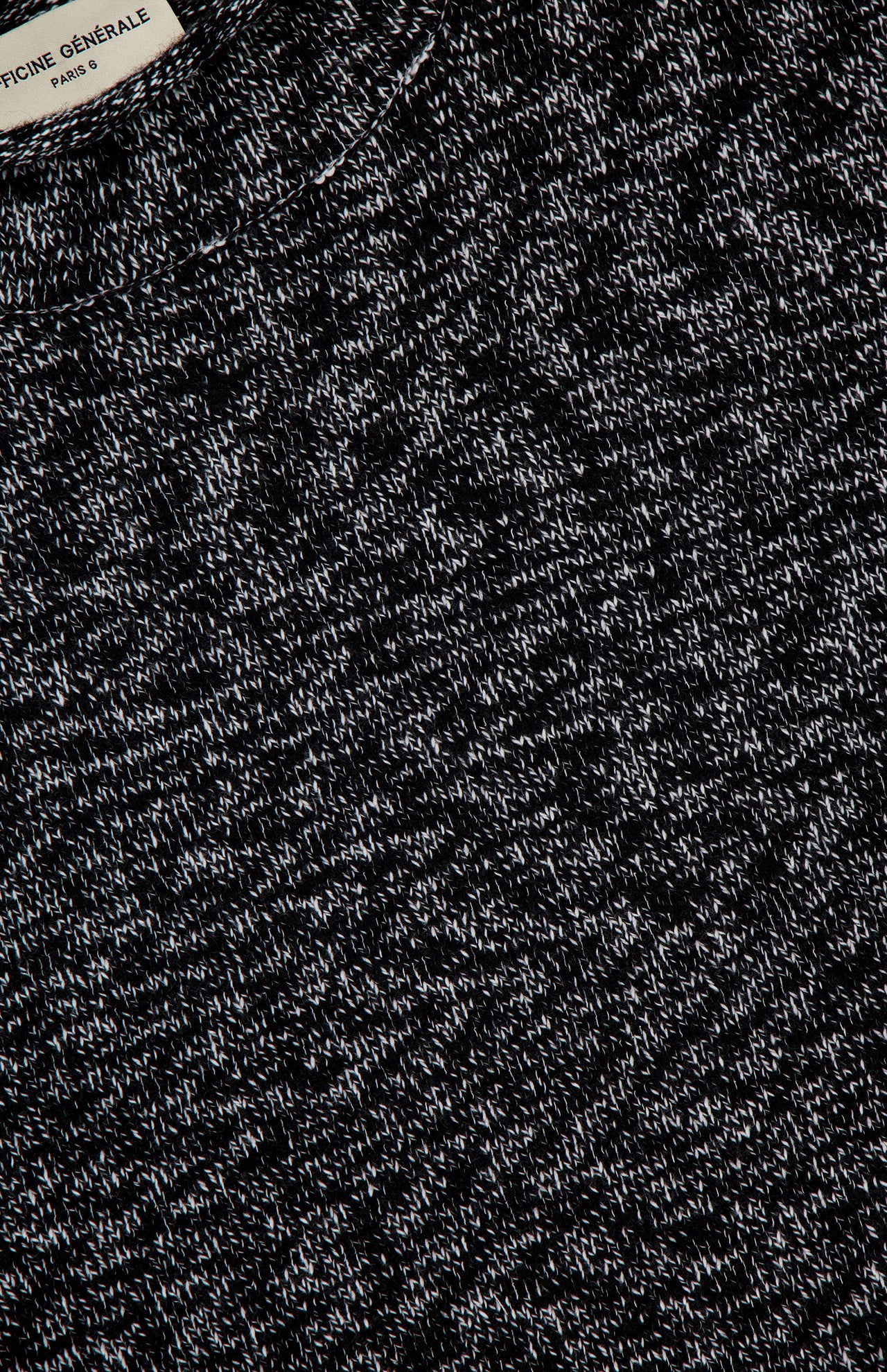 Close-up of the Riley Mockneck Sweater in black and cream, featuring a heathered pattern and Parisian-inspired knit top style. A partial view of the OFFICINE GÉNÉRALE label is visible at the top left corner.