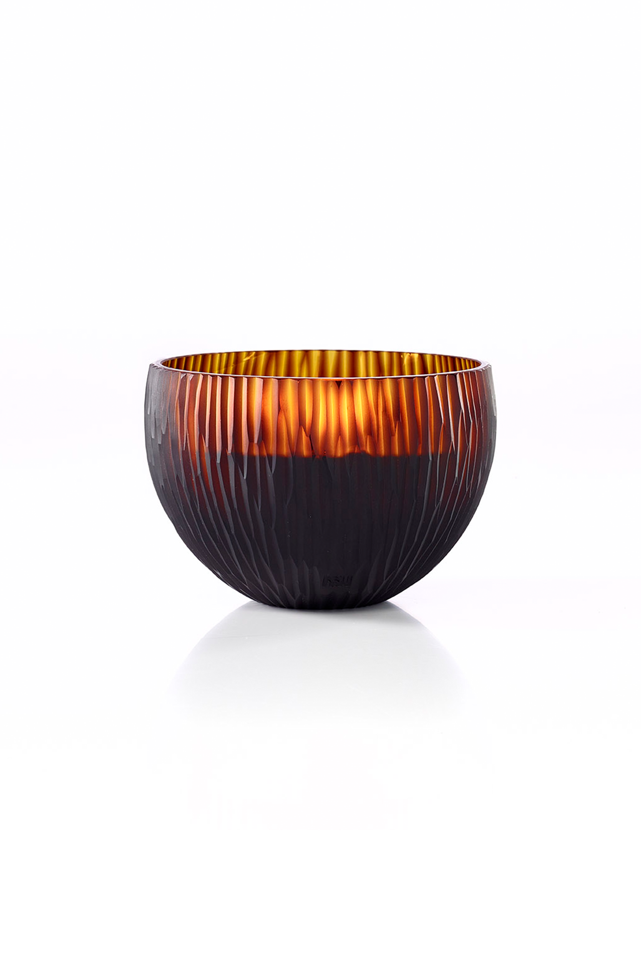The ONNO Amber Ellipse L Ginger Fig Candle is shown against a white background. Its round, amber glass bowl features a ribbed texture and glows warmly inside, highlighting the candle's translucent quality and inviting ambiance.