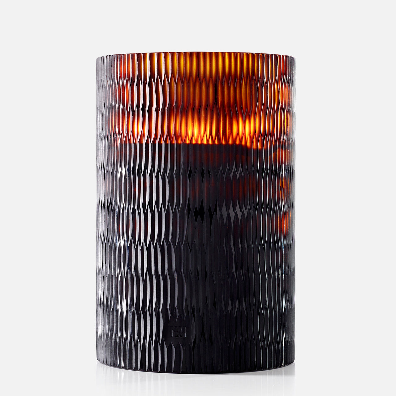 The ONNO Amber Rhombus L Ginger Fig Candle glows warmly in its textured, dark amber glass holder with a rhombus pattern, adding designer home fragrance to any space.