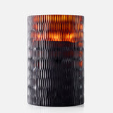 The ONNO Amber Rhombus L Ginger Fig Candle glows warmly in its textured, dark amber glass holder with a rhombus pattern, adding designer home fragrance to any space.