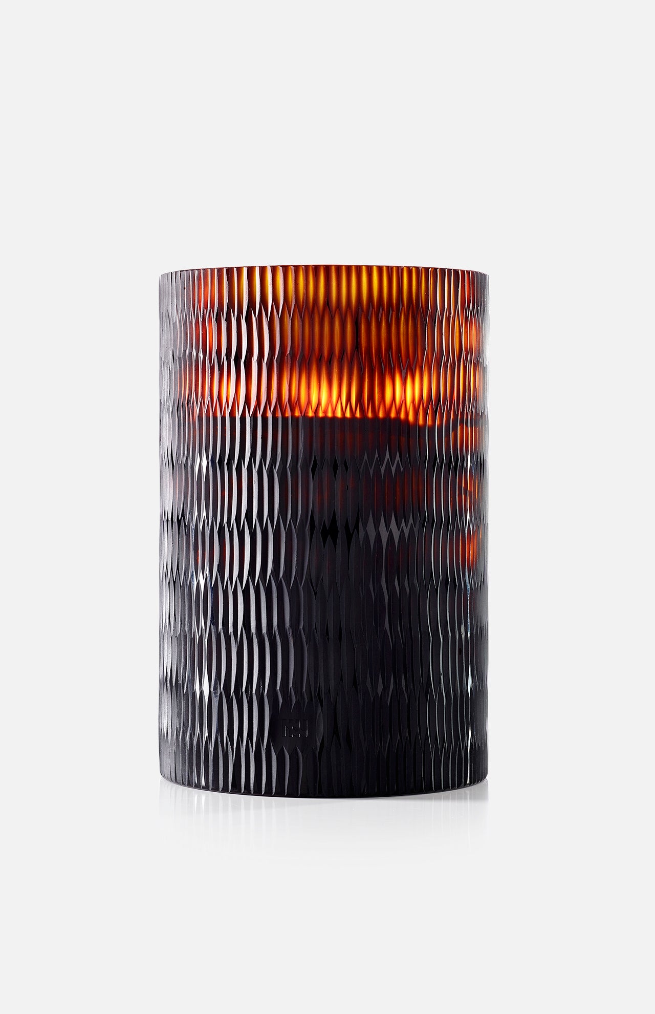 The ONNO Amber Rhombus L Ginger Fig Candle glows warmly in its textured, dark amber glass holder with a rhombus pattern, adding designer home fragrance to any space.