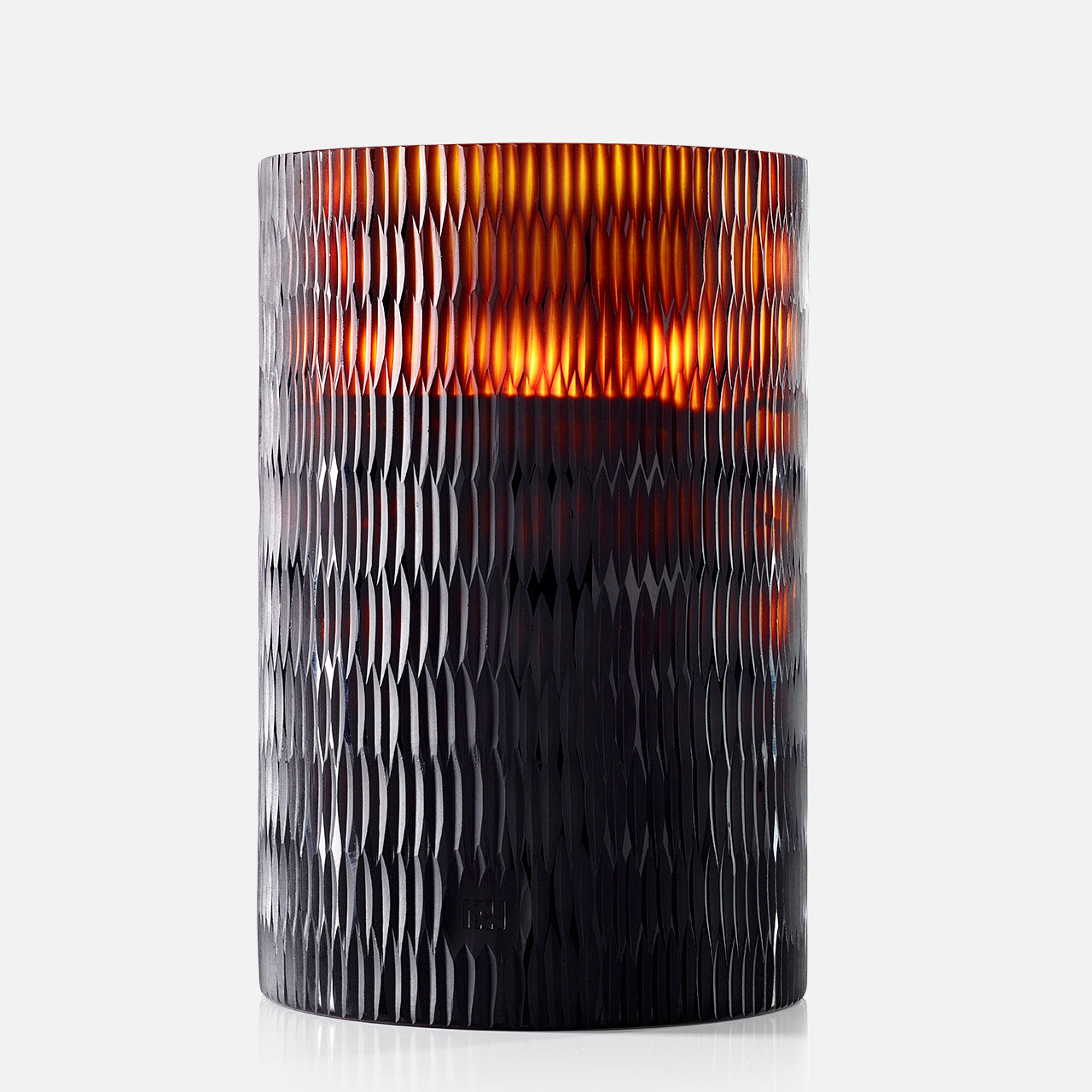 The ONNO Amber Rhombus L Sage Candle glows warmly in a dark, textured glass holder with a honeycomb pattern, creating an inviting ambiance against a plain white background.