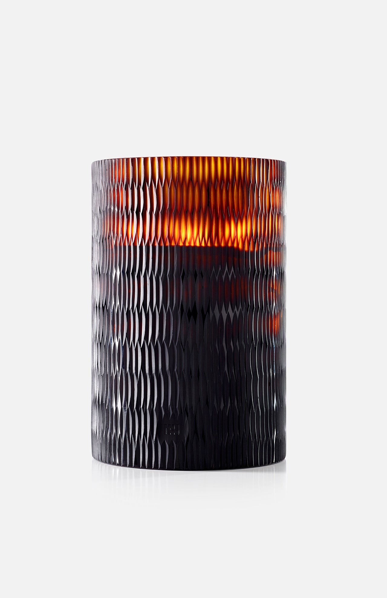 The ONNO Amber Rhombus L Sage Candle glows warmly in a dark, textured glass holder with a honeycomb pattern, creating an inviting ambiance against a plain white background.