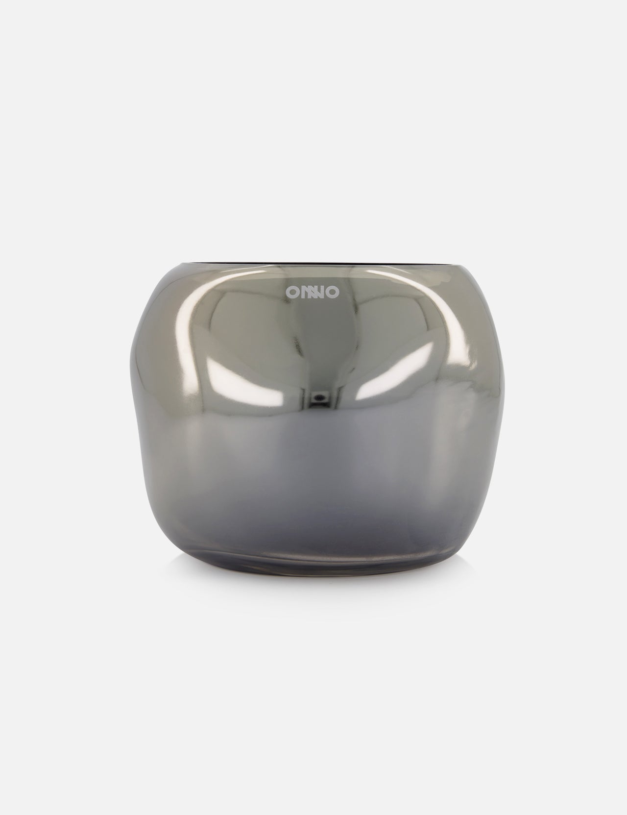 A reflective, rounded Cape Smoked Grey M Sage glass candle holder by ONNO, with a smooth metallic gray finish and subtle ONNO branding on the front, is displayed against a plain white background, embodying refined luxury.