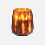 The ONNO Embrace L Sage Candle, set in a brown faceted glass holder with vertical ridges and a tapered shape, emits a warm golden glow—perfect as luxury designer decor against a plain white background.