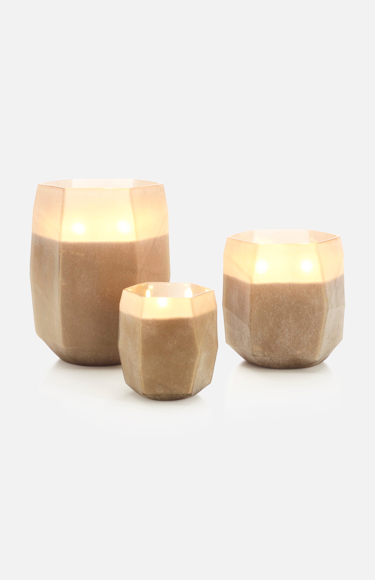 The ONNO Terre Light Smoked XL Zanzibar Candle glows warmly inside a faceted beige holder, creating an elegant display on a plain white background.