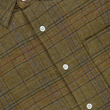 A close-up of the ORIGINAL MADRAS Check Straight Collar Dress Shirt showcases its green plaid Madras check, accented with red, blue, and brown lines in a classic checkered pattern. The white buttons and a yellow clothing label on the collar complement the shirt, which is crafted from pure Indian cotton.