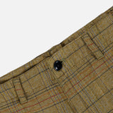 Close-up of the Check Trouser Pant by ORIGINAL MADRAS, featuring brown plaid fabric with belt loops and a black button at the waistband. The distinctive Madras check pattern in red and blue lines highlights these classic cotton trousers, made in India.
