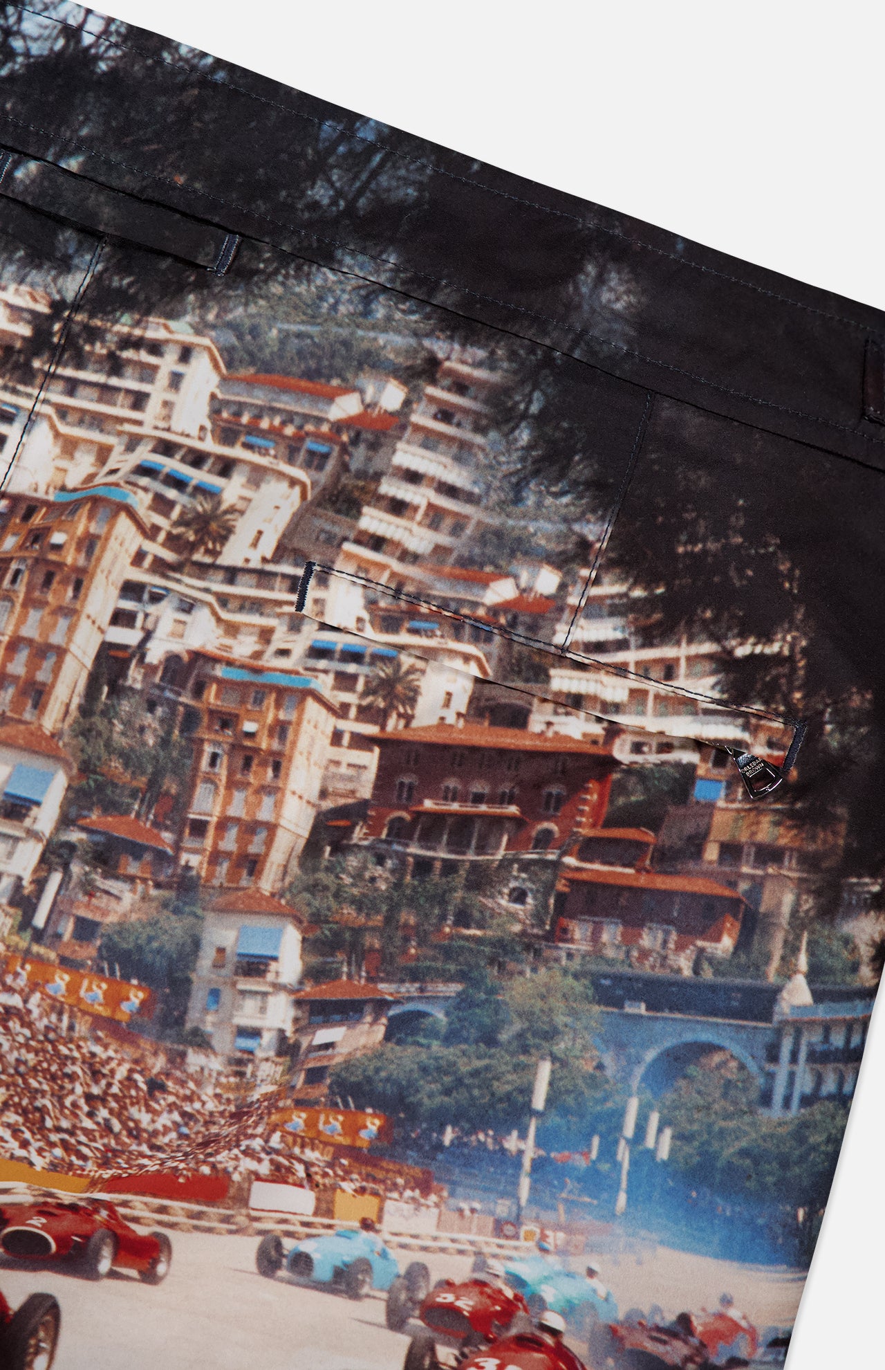 A close-up of ORLEBAR BROWN's Bulldog Photographic Race Car Shorts, showing a vibrant Grand Prix de Monaco print with grandstand crowds, hillside buildings, and pocket stitching—ideal for standout swimwear.