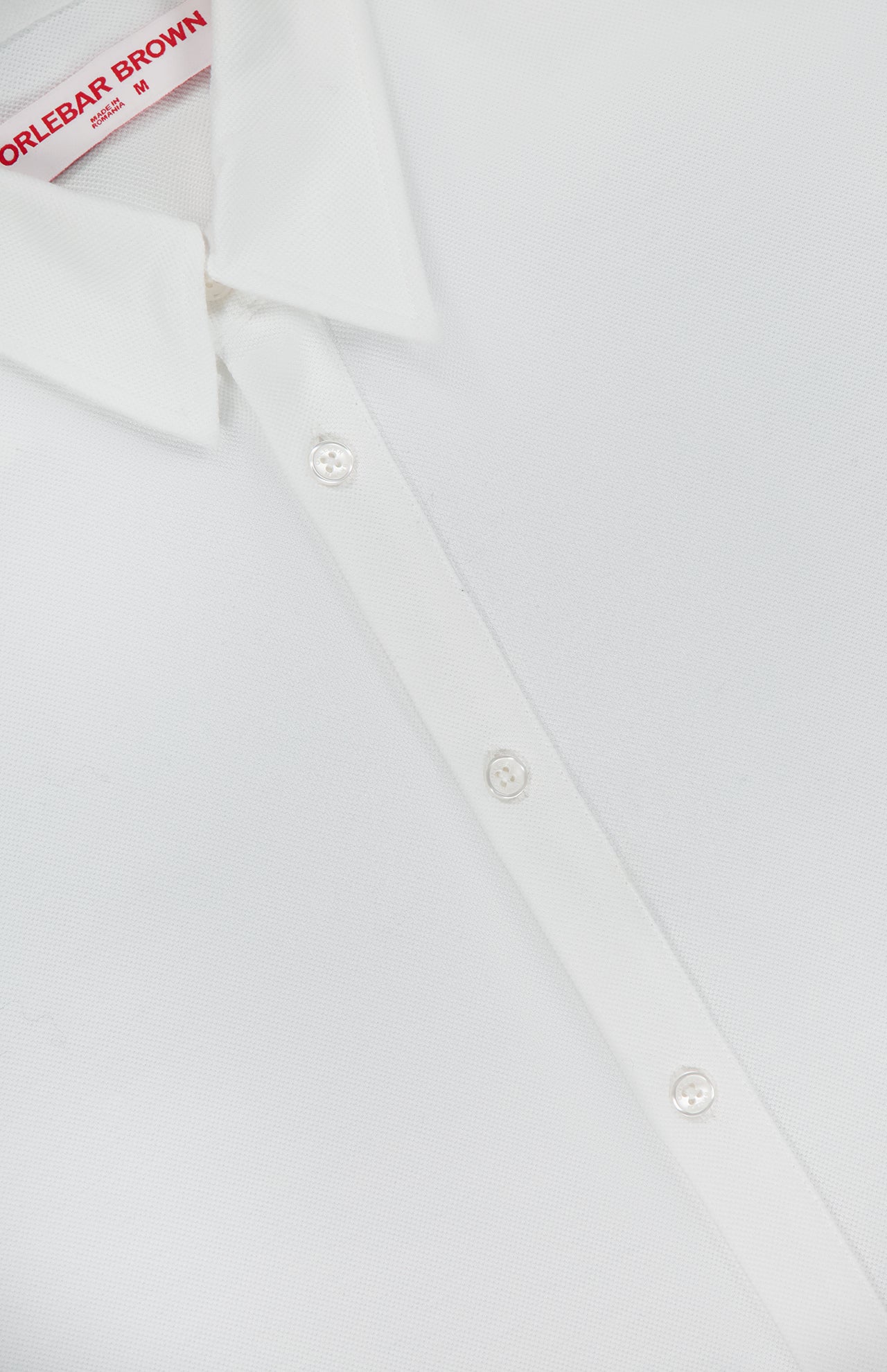 Close-up of the Giles Slim Fit Pique Shirt by ORLEBAR BROWN in Italian-woven cotton, partially unbuttoned with a visible red ORLEBAR BROWN size M label inside the collar.