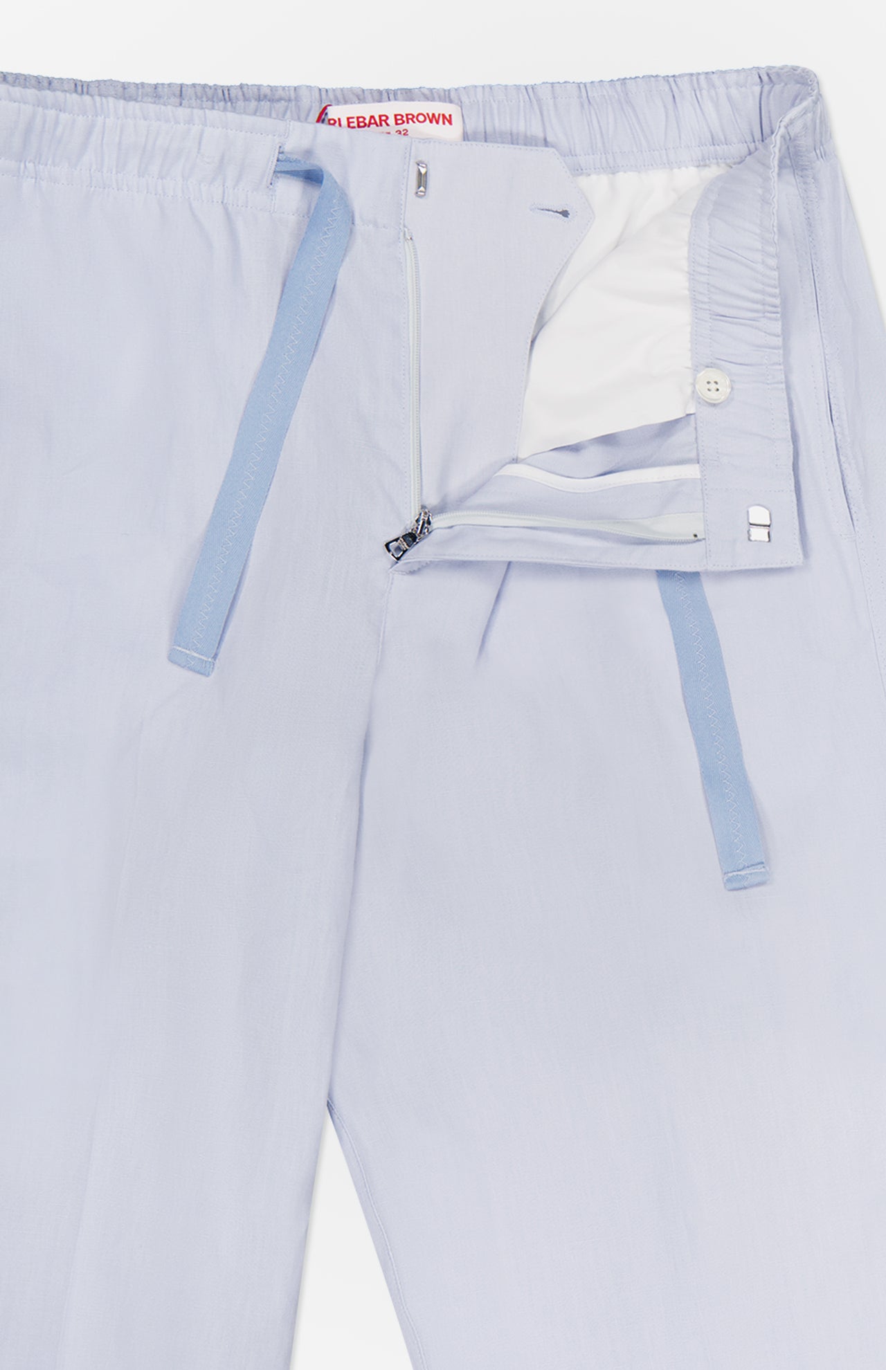 Alex Relaxed Linen Pants by ORLEBAR BROWN in light blue feature a relaxed fit, elastic drawstring waist with visible blue ties, partially open zip fly, inner lining, button fastening, and part of the brand label at the top.