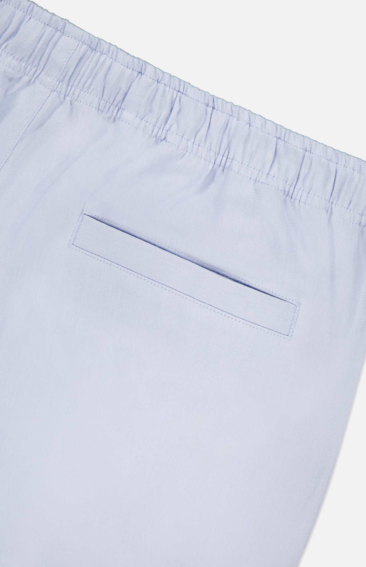 Close-up of ORLEBAR BROWN’s Alex Relaxed Linen Pants in light blue, featuring a relaxed fit, elastic waistband, and a single welt back pocket.