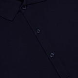 Close-up of the ORLEBAR BROWN Bruno 3 Button Pique Polo Shirt in dark navy, showing its classic fit, textured cotton pique fabric, collar, three-button front placket, and a visible clothing label at the top left.