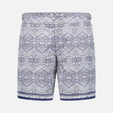 The ORLEBAR BROWN Bulldog Carnival Swim Trunk features a blue and white paisley print, elastic waistband, adjustable side buckles, and dark blue stripes at the bottom, displayed on a plain white background.