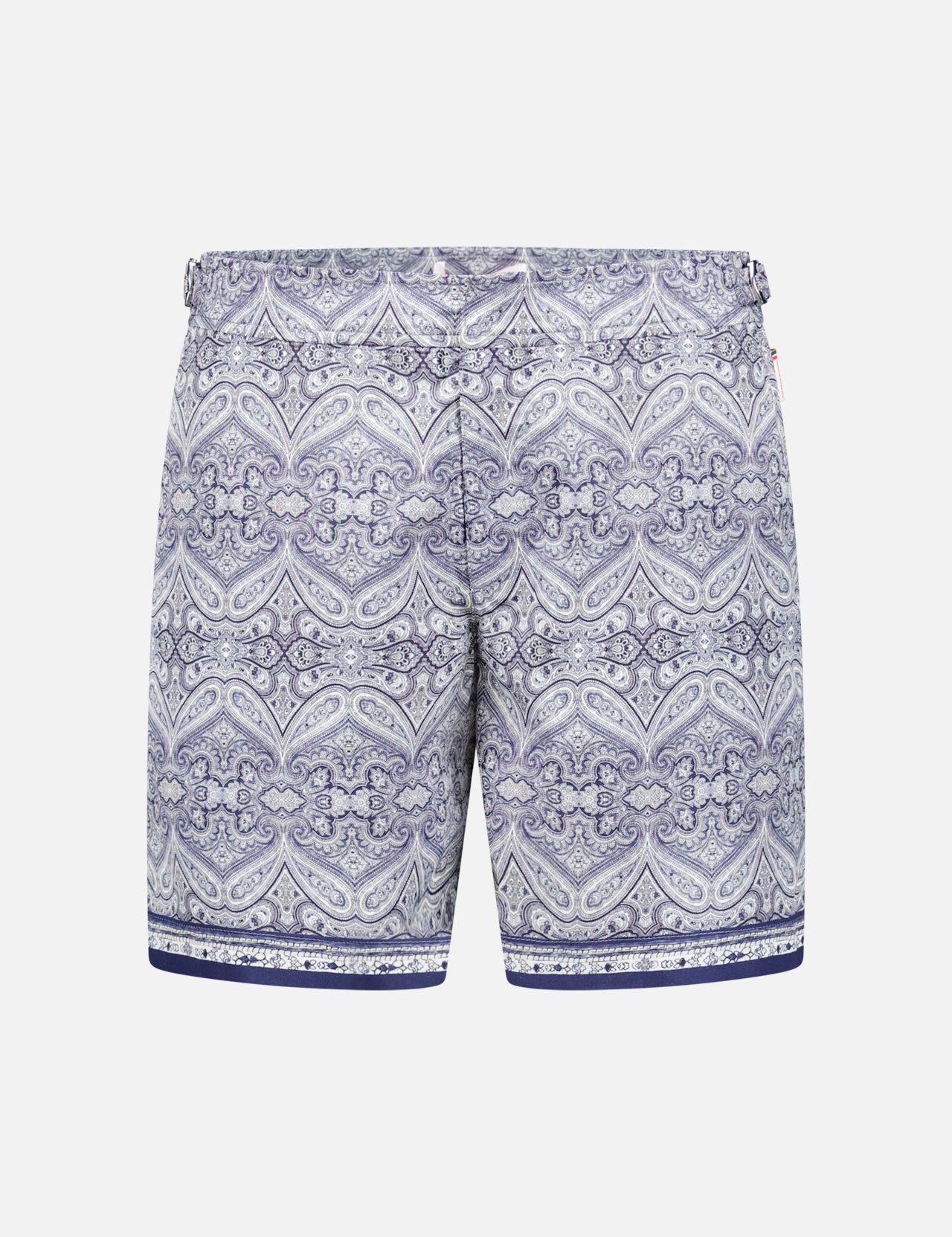 The ORLEBAR BROWN Bulldog Carnival Swim Trunk features a blue and white paisley print, elastic waistband, adjustable side buckles, and dark blue stripes at the bottom, displayed on a plain white background.