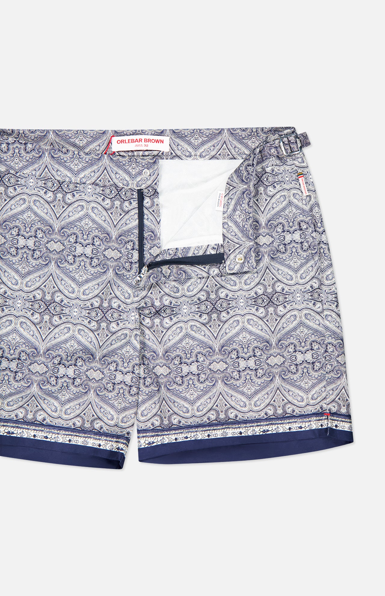 The ORLEBAR BROWN Bulldog Carnival Swim Trunk features a blue and white paisley print, front snap and zip closure, inner white mesh lining, and adjustable side buckles for a perfect fit.