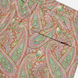 Close-up of ORLEBAR BROWN's Bulldog Drawcord Carnival Paisley Swim Shorts, featuring colorful green, pink, yellow, and red paisley print with visible seams and part of a pocket.