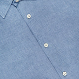 A close-up of the ORLEBAR BROWN Giles Lino Stitched Shirt in light blue linen features white buttons, a pointed collar, and a partially visible red and white ORLEBAR BROWN label at the top.