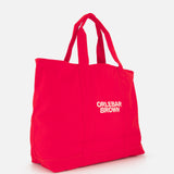 The Beach Bound Bag by ORLEBAR BROWN is a bright red organic cotton canvas tote with two handles and “ORLEBAR BROWN” in white on the front, shown against a plain white background.