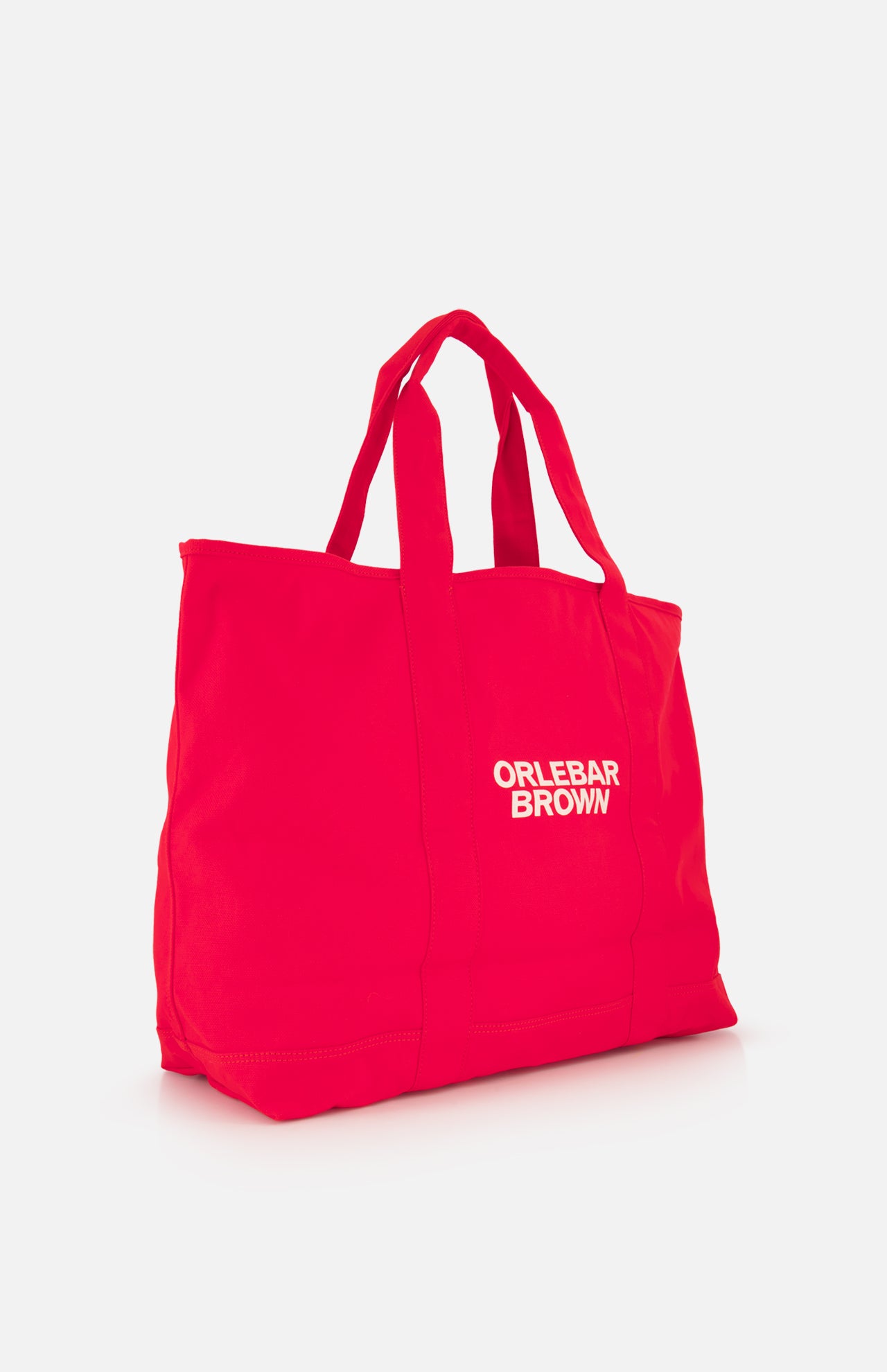 The Beach Bound Bag by ORLEBAR BROWN is a bright red organic cotton canvas tote with two handles and “ORLEBAR BROWN” in white on the front, shown against a plain white background.