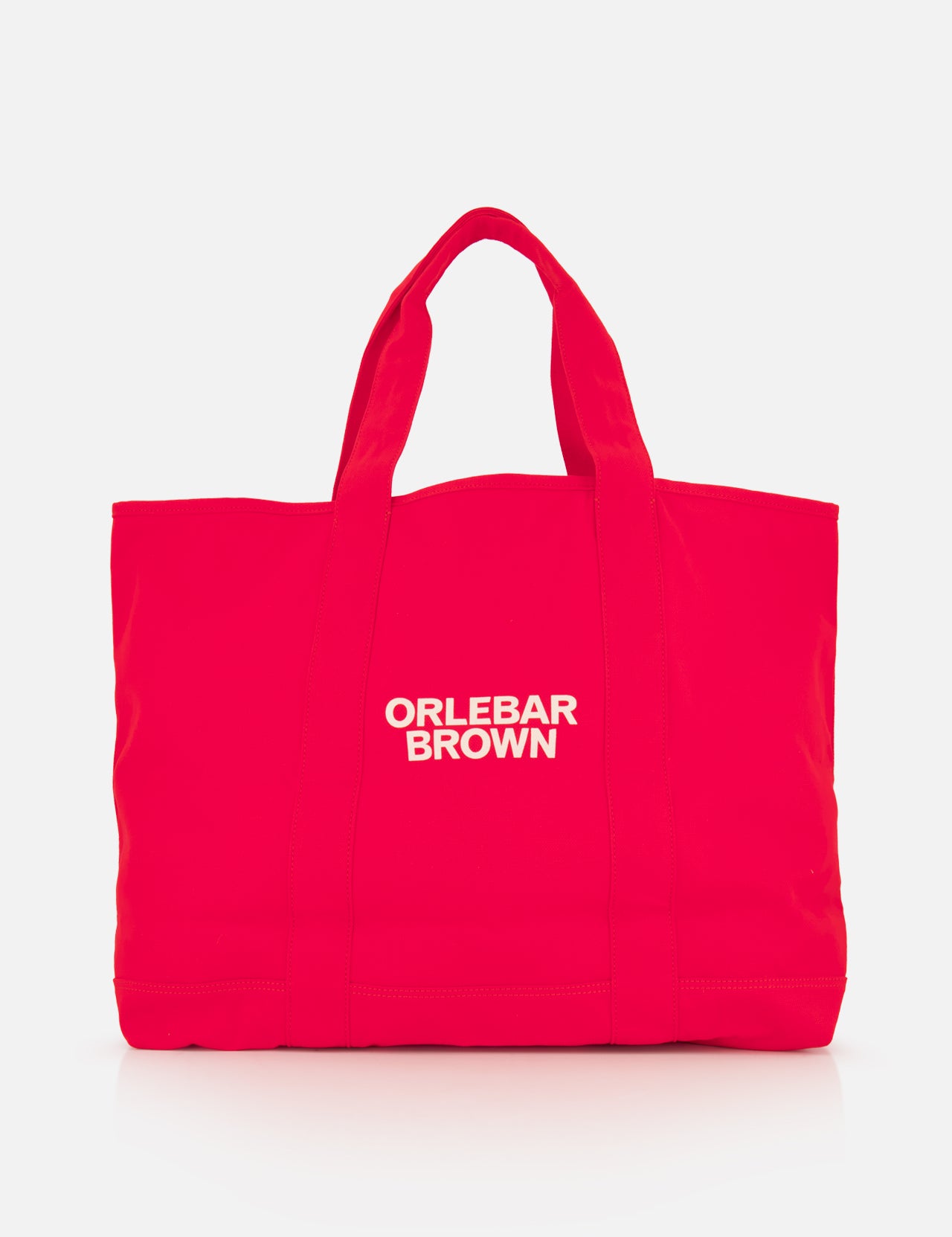 The Beach Bound Bag by ORLEBAR BROWN is a bright red organic cotton canvas tote with two handles and a white centered logo, shown on a plain white background.