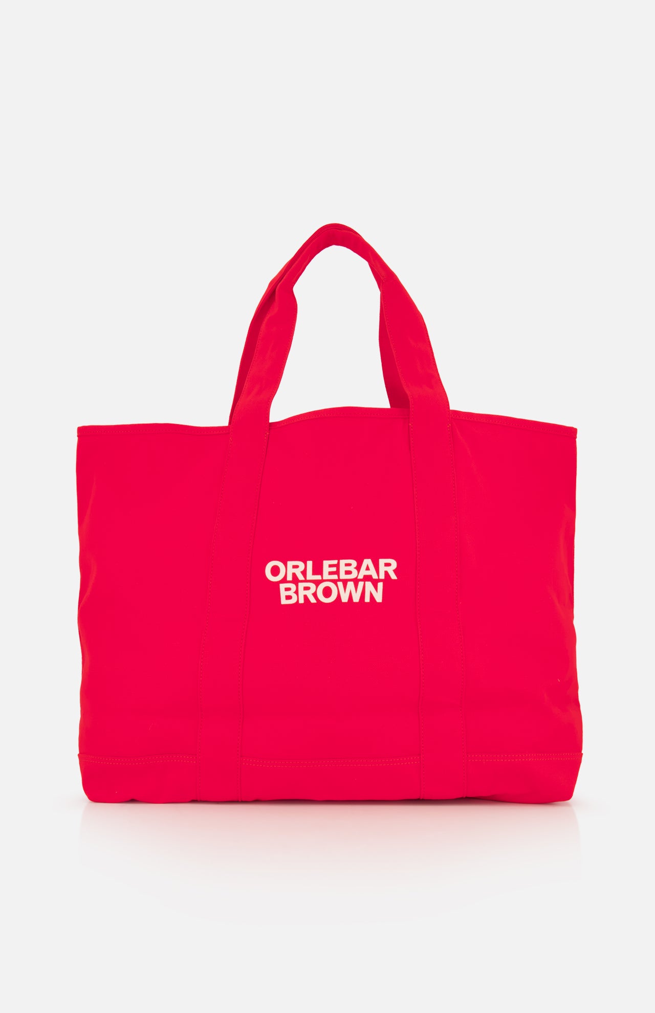 The Beach Bound Bag by ORLEBAR BROWN is a bright red organic cotton canvas tote with two handles and a white centered logo, shown on a plain white background.