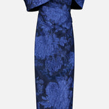PAMELLA ROLAND’s Fil Coupe Off The Shoulder Gown features a fitted, off-the-shoulder silhouette with an asymmetrical neckline and textured crinkled floral fil coupé pattern on a light gray background.