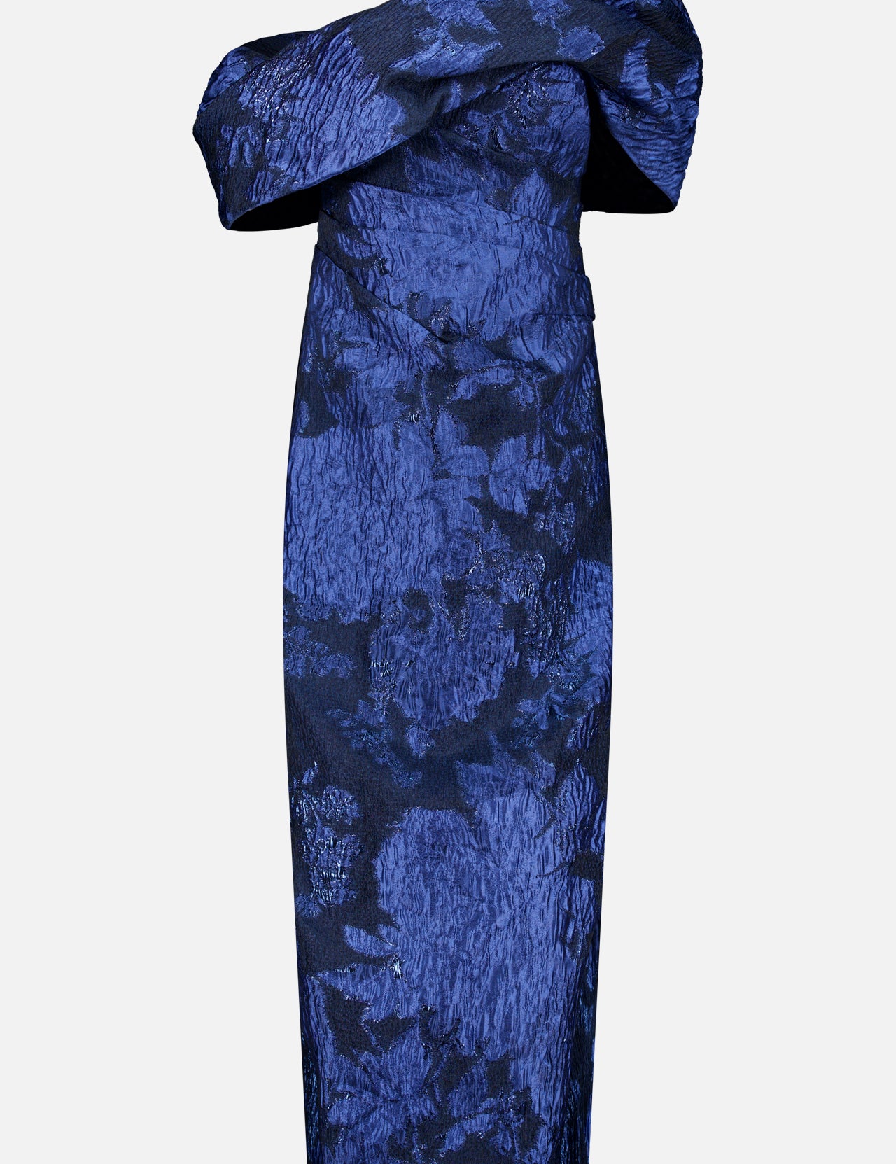 PAMELLA ROLAND’s Fil Coupe Off The Shoulder Gown features a fitted, off-the-shoulder silhouette with an asymmetrical neckline and textured crinkled floral fil coupé pattern on a light gray background.