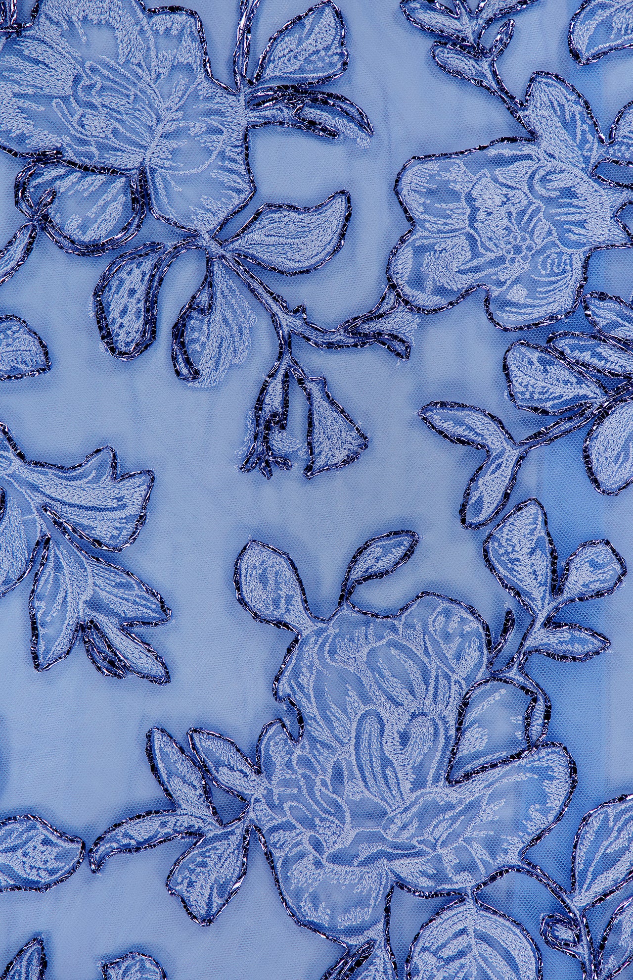 Close-up of the PAMELLA ROLAND Raffia Embellished Gown, showcasing delicate blue floral lace with shimmering embroidery on a sheer light blue background—ideal for special occasions.