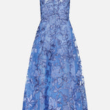 The PAMELLA ROLAND Raffia Embellished Gown is a sleeveless cornflower blue dress with a sheer overlay, floral embroidery, fitted bodice, tea-length flared skirt, zipper back closure, and elegant detailing—perfect for special occasions.