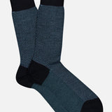 A pair of Blenheim Birdseye Merino Wool Socks featuring a dark blue and black textured pattern with solid black cuffs, heels, and toes.