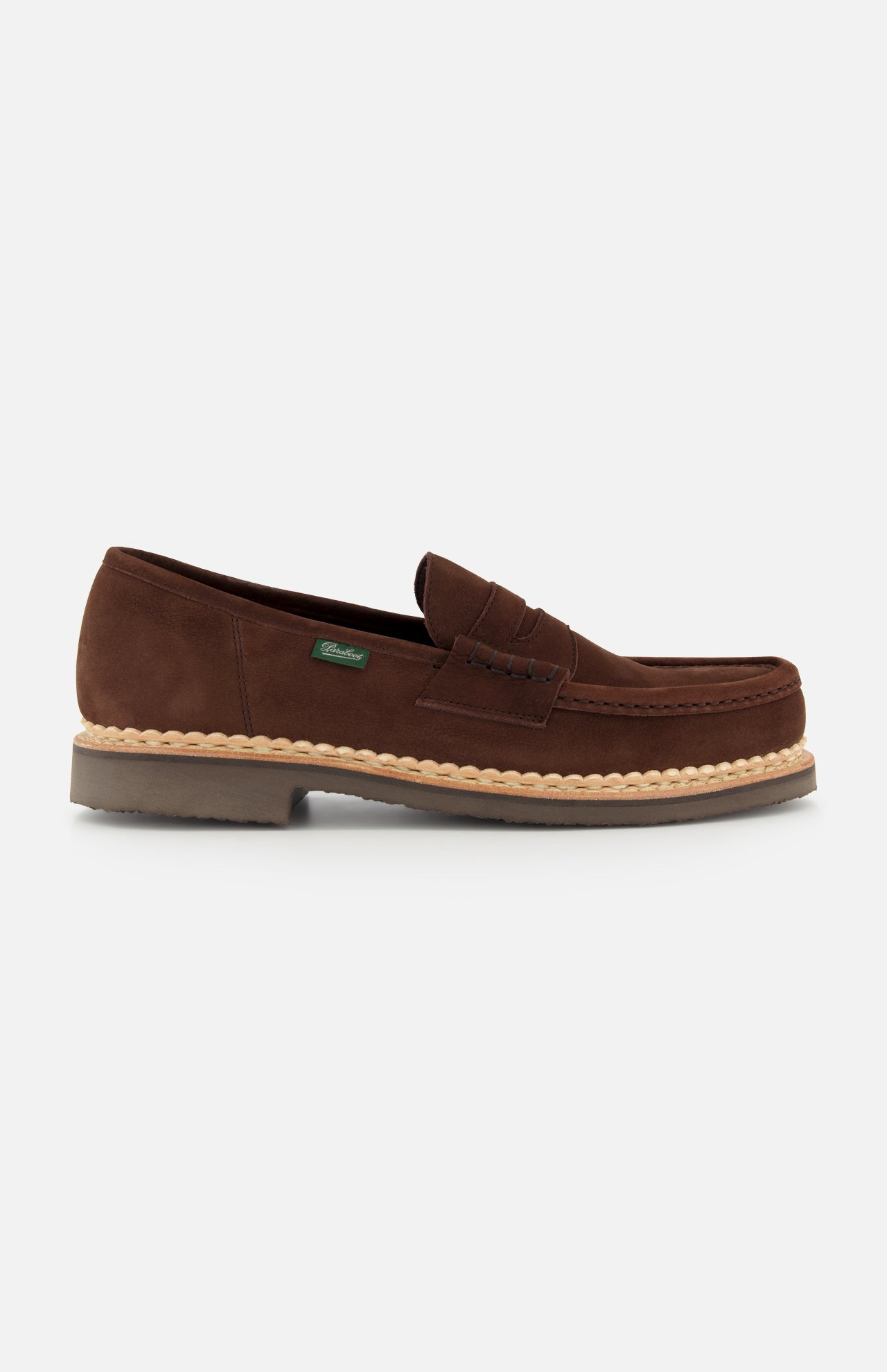 The Paraboot Nantes Slip On Loafer features brown suede, a moccasin-style toe with visible stitching, Norwegian welt construction, a tan rubber sole, and a small green side tag, shown against a plain white background.