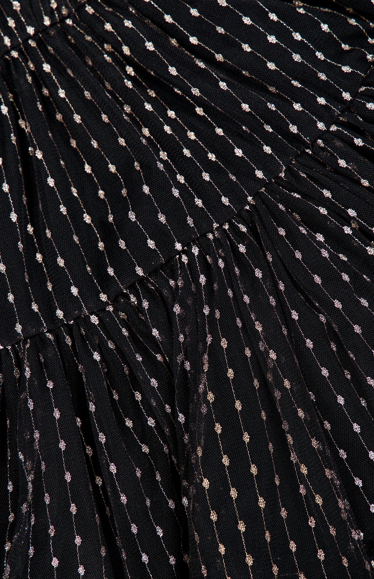 Close-up of the Olga Tulle Short Dress by PATBO showcases black sheer tulle adorned with diagonal rows of small, evenly spaced white dots, creating a textured and layered effect—an elegant detail ideal for enhancing a halter neckline party dress or mini dress.