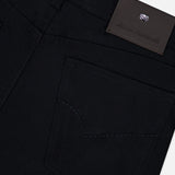 Close-up of the back pocket and waistband of the PESCAROLO Nerano M Cashmere Pants, featuring intricate stitching and a dark leather patch embossed with text and a small logo above the pocket. The classic 5-pocket design enhances the timeless appeal of these black cashmere pants, showcasing exceptional craftsmanship.